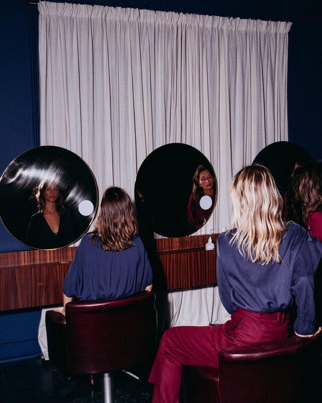 Clients and stylists at three round mirrors in an elegant hair salon.